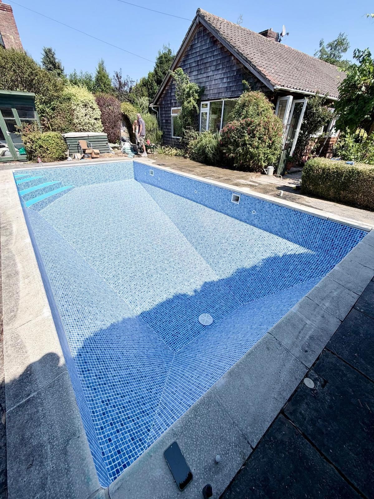 The same pool with a new blue mosaic-effect liner after renovation