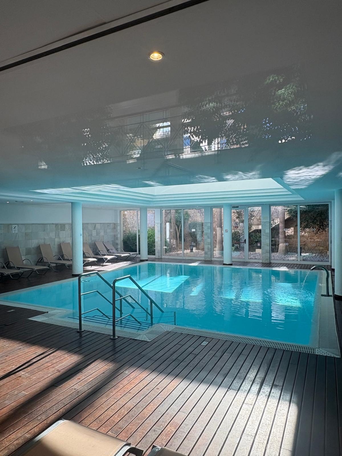 Indoor swimming pool with timber decking and garden views