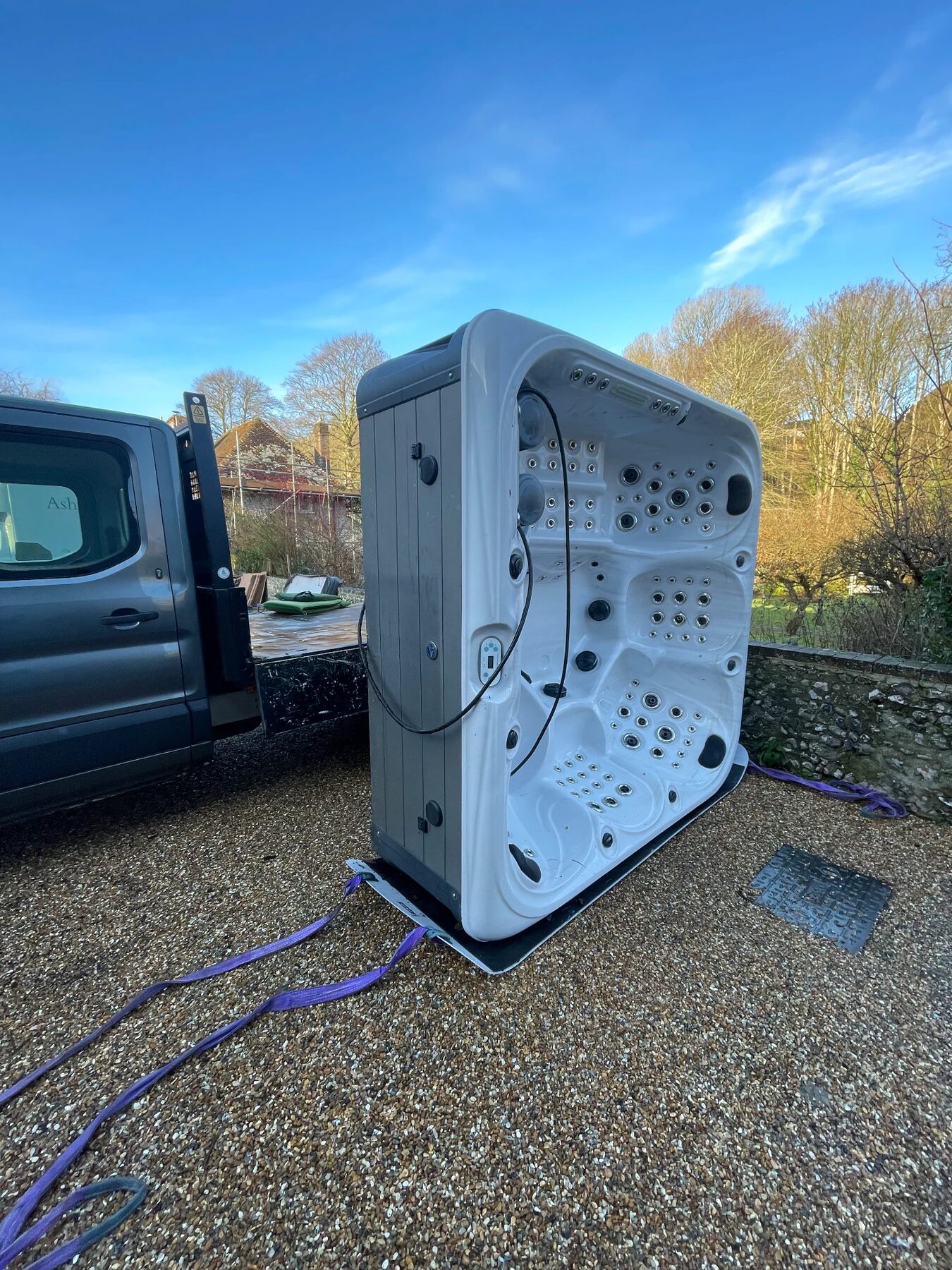 Hot tub being delivered on edge from a StarLuxe vehicle to a customer's garden