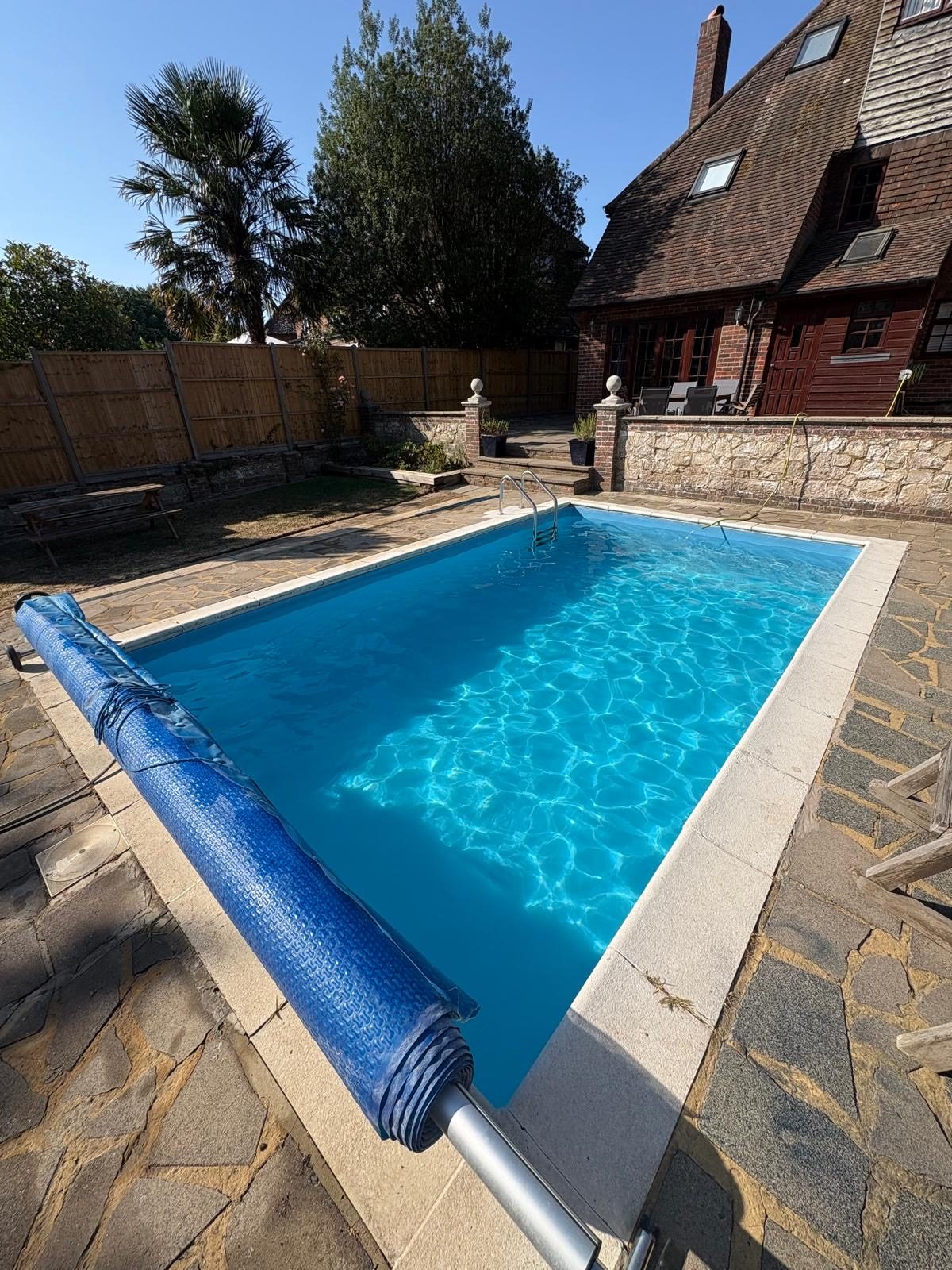 Rectangular pool with a roller cover beside a house