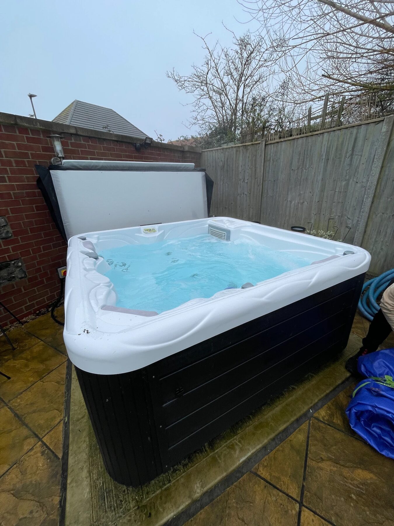 Family hot tub with open cover on a paved patio in West Sussex