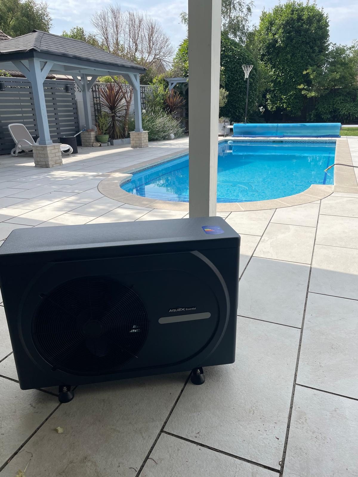 Pool heat pump positioned beside an outdoor swimming pool