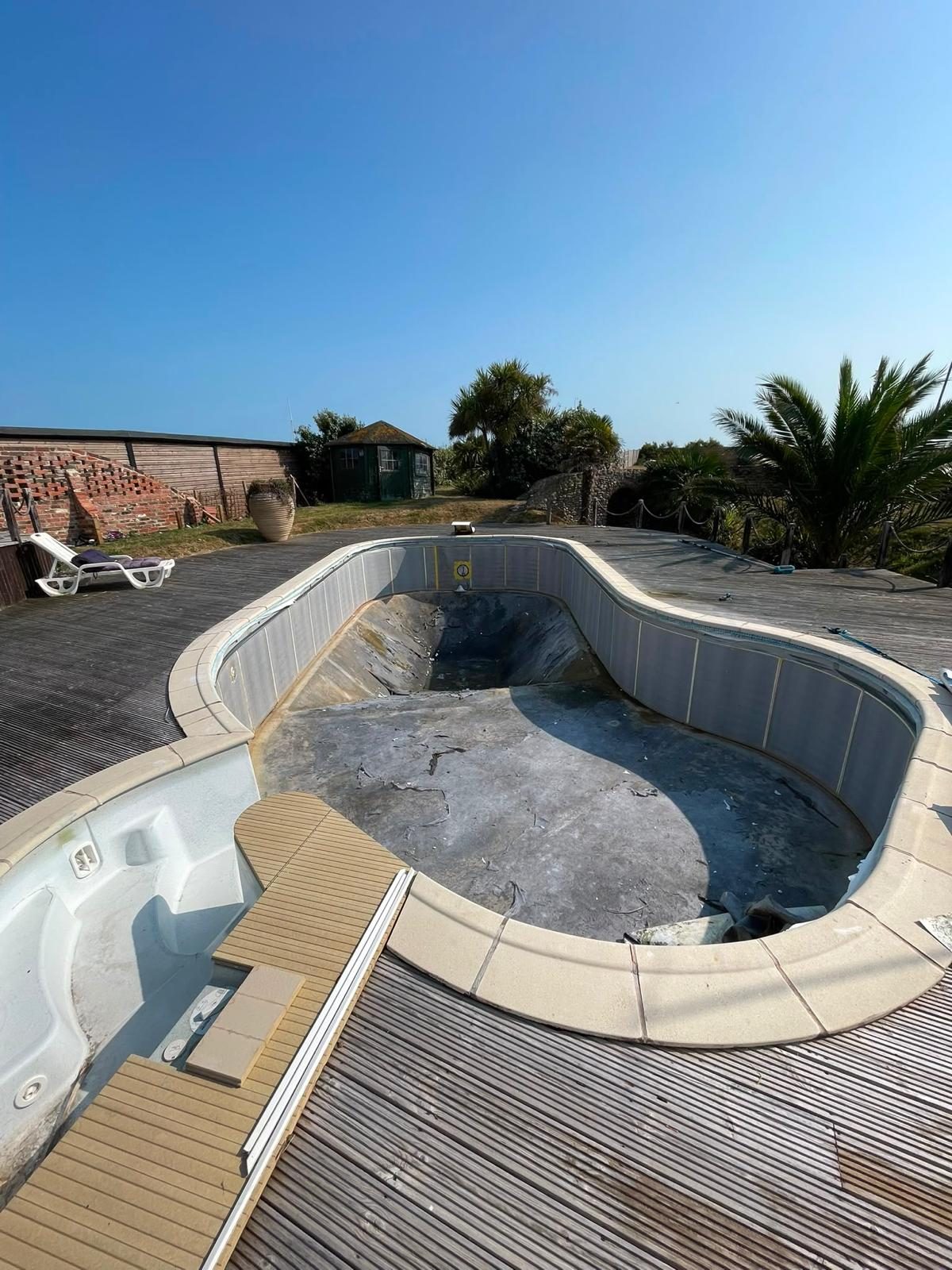 Empty freeform pool with a worn interior before renovation